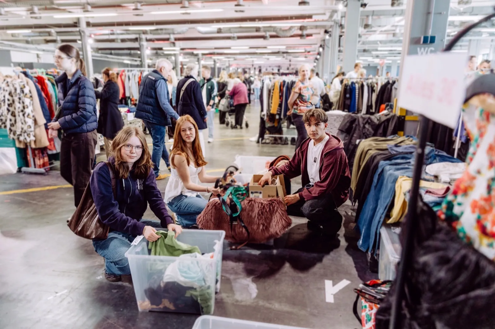 Verkäufer:innen bauen ihren Stand mit Kleiderständern auf dem Flowmarkt auf